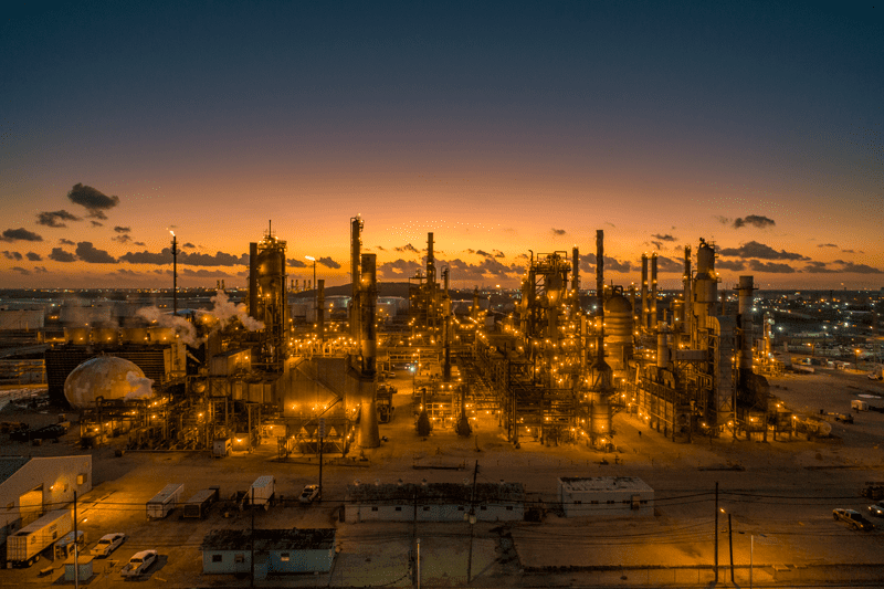 Moments before sunrise the refinery is lit up like the golden hues behind it. An aerial shot taken by drone.