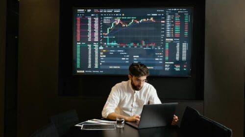 Businessman using laptop in office analyzing stock market charts. Professional finance and investment concept.