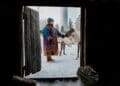 Sami petting reindeer with wind turbine background